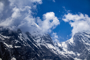 Naklejka premium Snow covered mountains against blue sky and cloud cover. Panchachuli peaks of himalaya