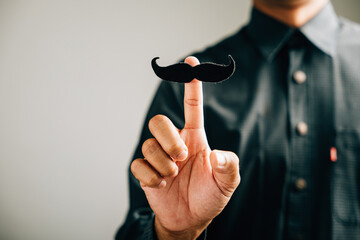 A man's unique gesture in holding a mustache signifies support for Prostate Cancer Awareness, stressing men's healthcare and World Cancer Day.