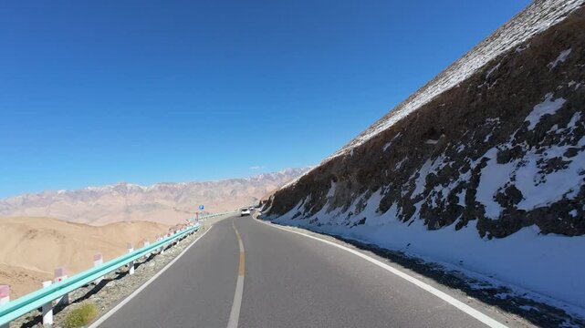 Driving on asphalt winding road passing through valley on sunny autumn day in Tashkurgan, Kashgar, Southern Xinjiang, China, POV from the car, 4k real time footage, travel concept.