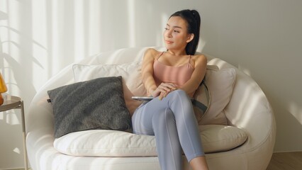Fototapeta premium Young woman relaxing on a sofa in a cozy living space.