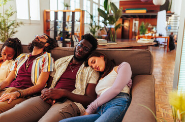 Obraz premium Four diverse people sleeping together on sofa