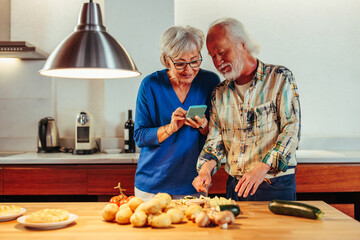 Senior couple reading recipe together while standing in kitchen.