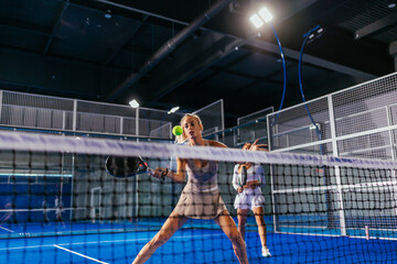 Blonde girl hitting a forehand during a doubles padel match