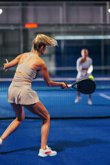 Rear view of an athletic young woman playing padel