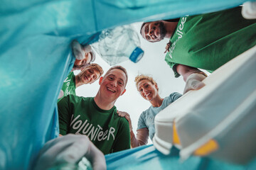 Volunteers collecting trash in garbage bag: