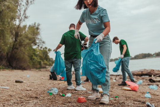 Volunteers collecting trash on river bank: environmental cleanup