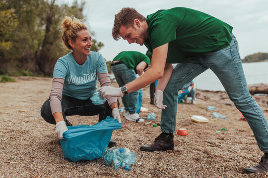 Volunteers collecting plastic waste on river bank: teamwork and environmental protection