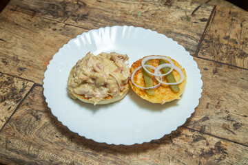 White plate with unnamed dish, capsicum variety foods with Onion slice and mayonnaise in a wooden dining table
