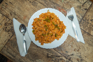 Spicy pasta with capsicum and place a spoon and fork, pasta placed in a wooden dining table, Italian spicy foods in India