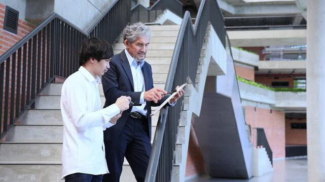 Asian senior professor is giving advice to the college student on the research thesis while sitting in the university faculty for education, academic and business