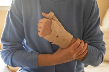 Person Holding Injured Hand With Wrist Brace For Pain Relief, Recovery, And Rehabilitation –...