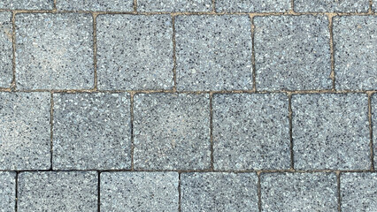 Obraz premium A gray brick wall with a gray stone tile. The wall is made of gray bricks and the tiles are gray