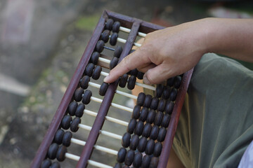 Close up man hand calculate and count wooden abacus. Concept, ancient style calculation. Counting equipment. Calculator. Educational material. Math teaching aid        