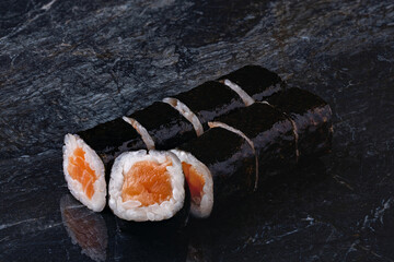 Japanese rolls, sushi maki in nori seaweed with salmon on a black marble background. © TrapezaStudio