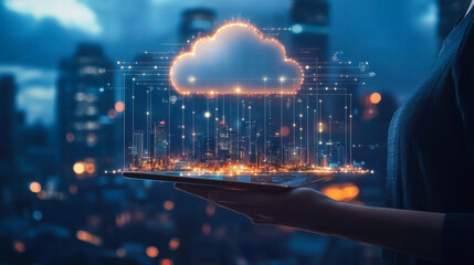 A person holding a tablet displaying a digital cloud over a city skyline during twilight with urban lights glowing in the background