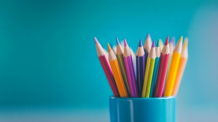 Fototapeta premium Vibrant colored pencils stand tall in a bright blue container for creative expression and art projects
