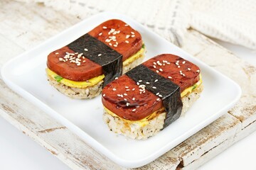 Classic Hawaiian spam musubi, made with grilled spam, seasoned rice, and wrapped with nori seaweed. A delightful fusion snack that combines savory, salty, and umami flavors in each bite.