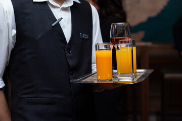 Waiter holding tray with orange juice and wine glasses