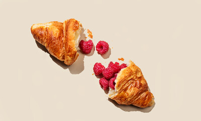 Flat lay of broken croissant with fresh raspberries on orange background. Creative mockup and concept of healthy food or pastry for breakfast.