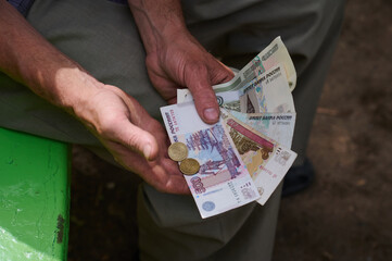 A man holds money of the Russian Federation in his hands. Banknotes and coins of different types. The concept of monetary settlements in cash.