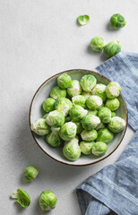 Fresh brussels sprouts in a bowl on a light gray background with napkin. Vegetarian healthy food concept.