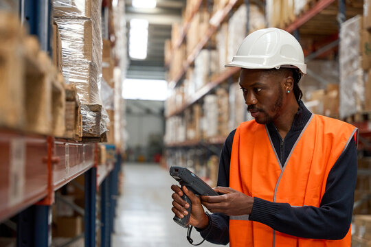 Warehouse worker scanning packages with barcode scanner in logistics center