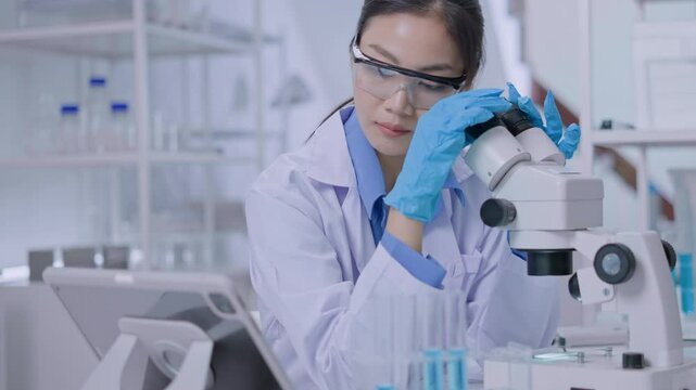 Asian Researcher using a microscope in the clinical lab.Female Researcher working in the clinical laboratory,Medical or scientific researcher or Asian woman doctor looking at professional microscope.