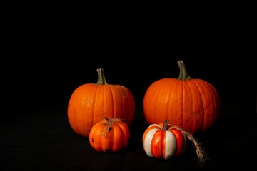 Two pairs of pumpkins arranged on a table with a black background and copy space 