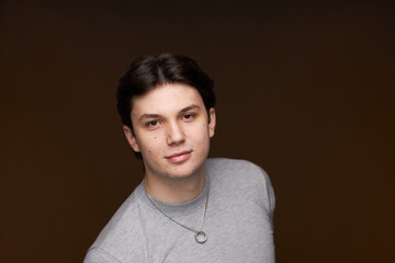 A Young Man in a Gray Hoodie Poses Confidently in a Studio Setting, Showcasing a Relaxed yet Engaging Expression