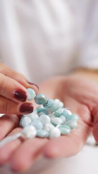 Make Bracelets From Natural Stones .Jewelry designer arranging amazonite beads on hands on white table