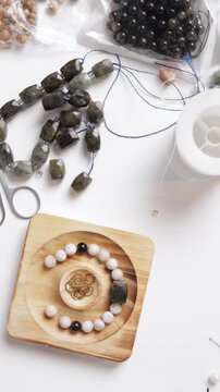 Make Bracelets From Natural Stones .Jeweler adding beads to bracelet on white table