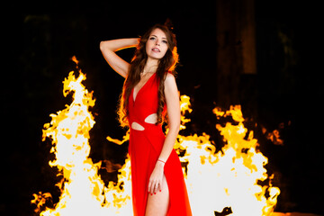 Fire and Grace: A young beauty in a red dress posing against a backdrop of flames