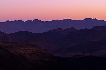 Silhuetas de Montanhas ao Anoitecer com Céu em Tons Suaves de Rosa e Roxo