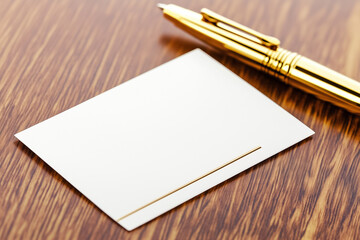 A stylish business card rests near a gleaming golden pen on a rich wood background, perfect for presentations