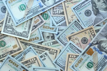 Many dollar bills with different nominations lies in big pile