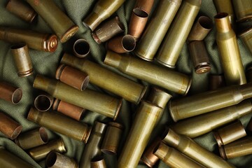 Many used rifle cartridges on military camo green fabric background