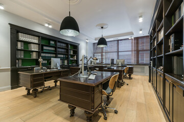 The interior of a modern office. Document cabinets and work desks are made of dark wood.