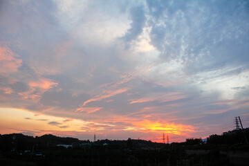 A dramatic sunset sky with colourful glowing clouds and a silhouetted landscape below
