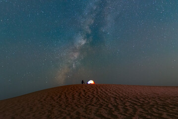 A camping tent in Beautiful night Stars milky way at oasis desert with date palm tree. © Piak