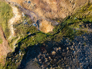 Aerial perspective of a geothermal river meandering through a colorful terrain, highlighting the unspoiled allure of iceland's natural environment