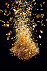 Obraz premium Gold particles burst in a dazzling show, shimmering in the dark and sparking wonder and excitement