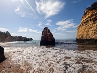 Impressive rock in the ocean of an Algarve beach in Portugal. Wild Atlantic coast landscape and natural shoreline textures during a bright summer day