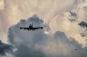 Large commercial jet airliner is descending through a cloudy sky.