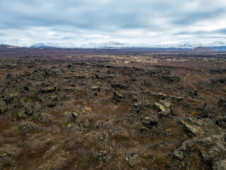 Beautiful aerial of the landscape featuring Dimmuborgir lava formations and snow-capped mountains in Iceland under a cloudy sky
