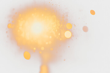 Abstract bokeh lights with warm yellow and orange glow against a dark background.