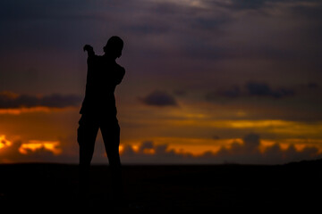Fototapeta premium silhouette of a person with a raised hands in sunset