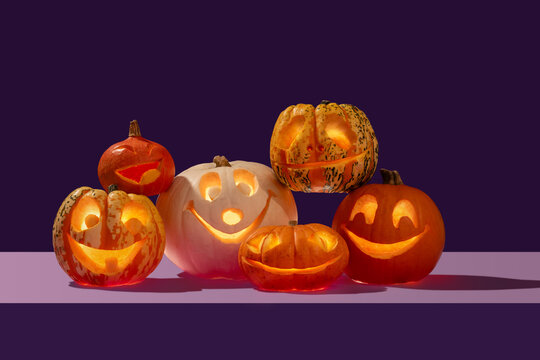 Halloween variety of happy face pumpkins gang on a pile like a singing choir in contrast orange and purple