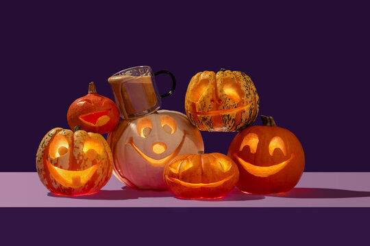Pumpkin spiced latte with Halloween variety of happy face pumpkins gang on a pile like a singing choir in contrast orange and purple.