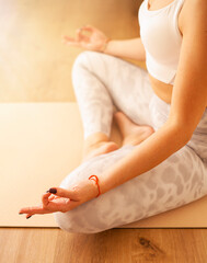 Young woman doing yoga at home, sitting in lotus position. Close up
