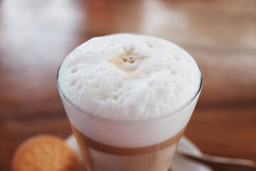 fresh hot latte coffee drink with milk foam on wooden table in cafe